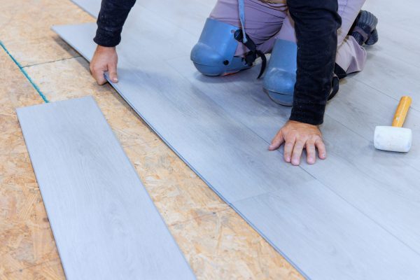 During installation vinyl laminate at floor of new home worker works